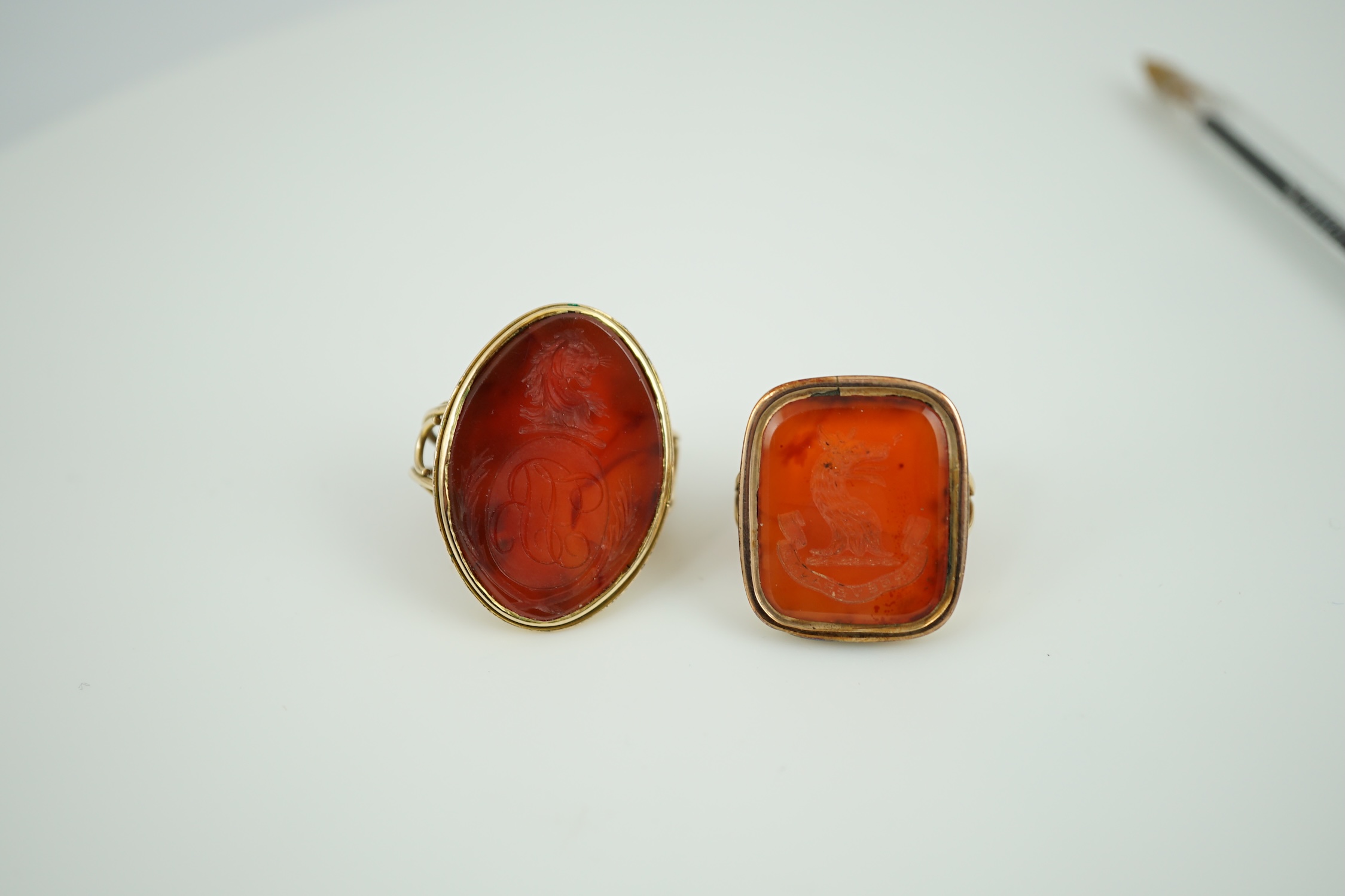 Two Victorian yellow metal and agate set intaglio rings, both matrix carved with a crest, one with monogram also, sizes K and L, gross weight 21.5 grams.